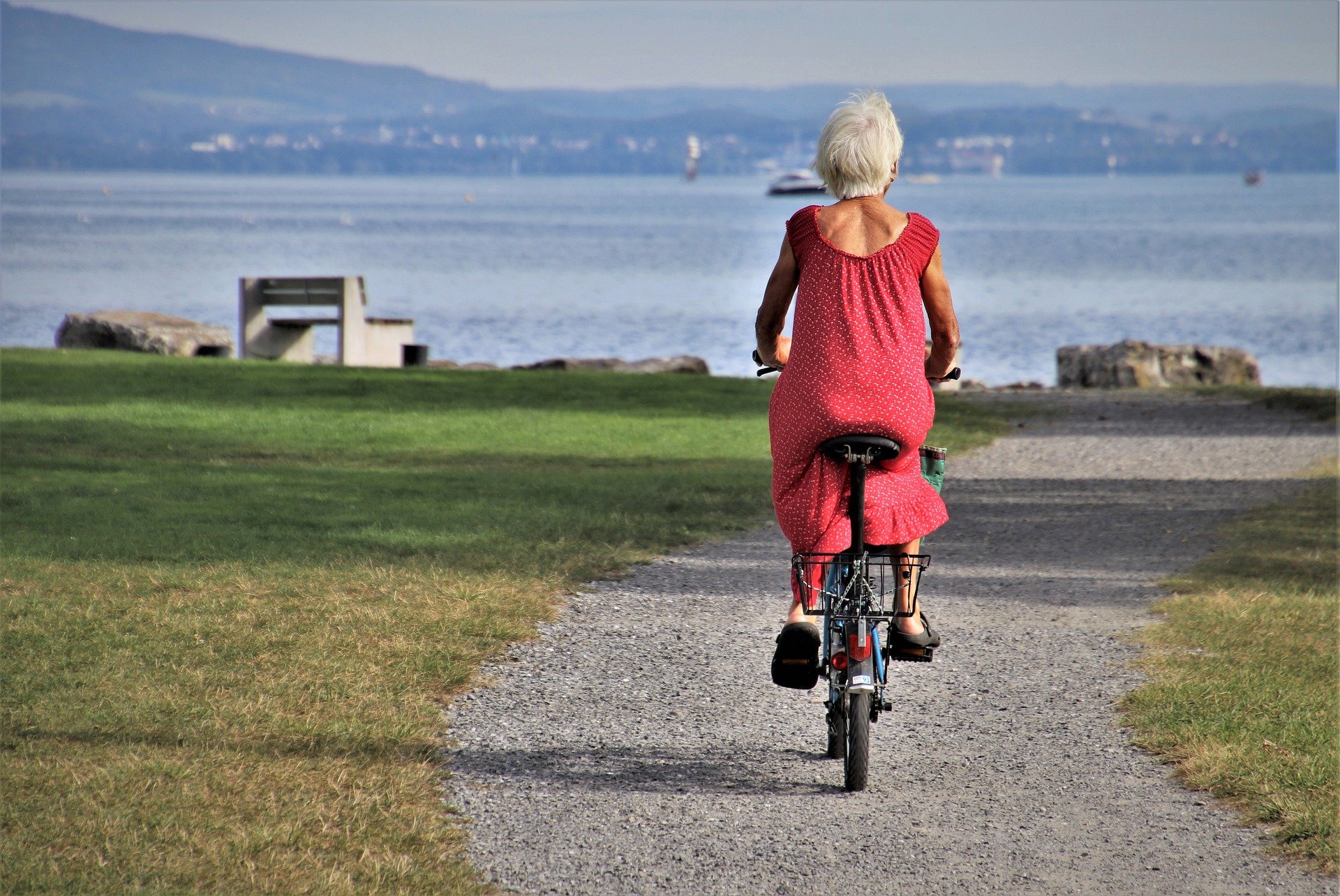 Ηλικιωμένη γυναίκα με ποδήλατο στην παραλία