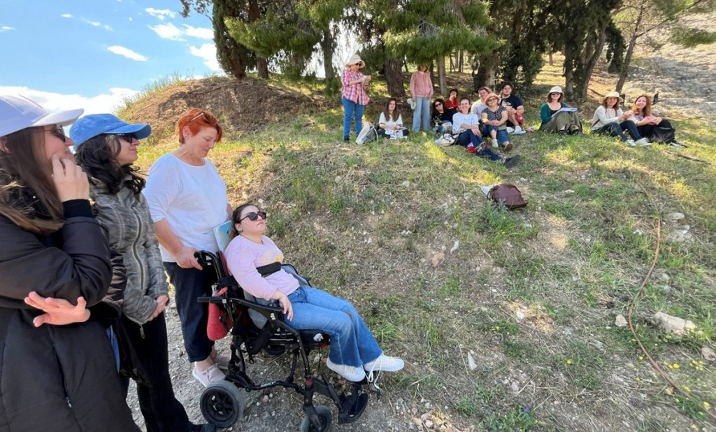 Ομάδα ανθρώπων σε εξωτερικό χώρο με άτομο σε αμαξίδιο