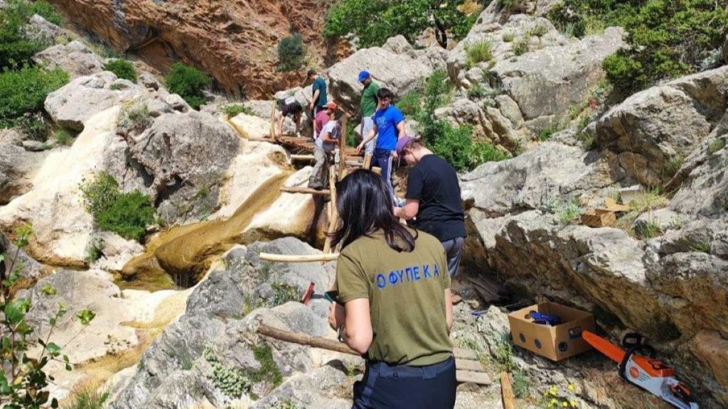 Ομάδα ανθρώπων που επισκευάζουν ξύλινο μονοπάτι στους καταρράκτες Λεπίδας, στο Μουστό